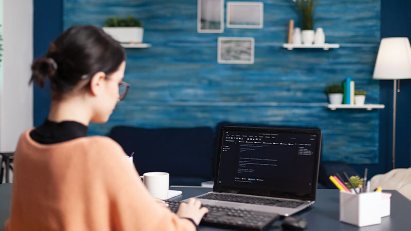 Realistic image of a person’s hand resting on a laptop keyboard with one finger of another hand approaching a search bar with the words “AI Search.