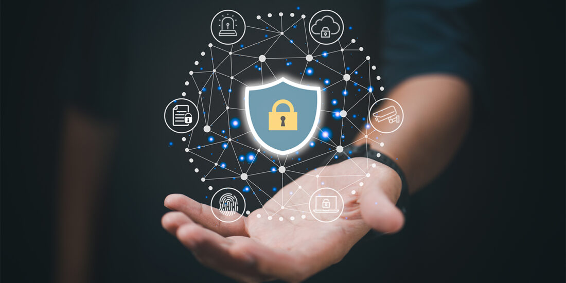 The image depicts a hand with a graphic overlay representing cybersecurity concepts. A shield icon with a lock symbol is central, surrounded by interconnected nodes symbolizing a network, each with icons such as a key, a padlock, a document, and a shopping cart, indicating various aspects of digital security. The background is dark, focusing the attention on the hand and the network of security symbols.