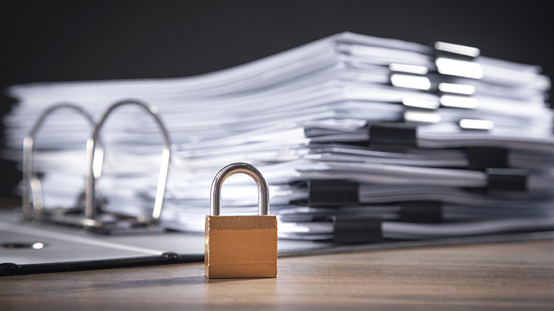 A binder full of confidential documents locked with a padlock. Businesses can use document imaging systems to scan and digitize their paper documents, making them less susceptible to loss or damage than physical copies.