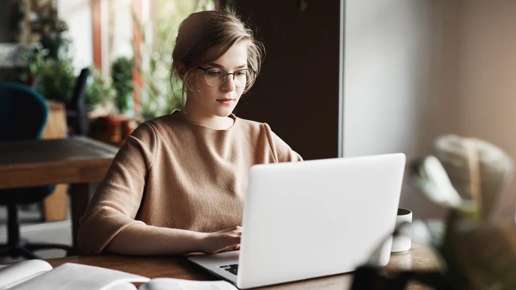 young woman in glasses working on laptop