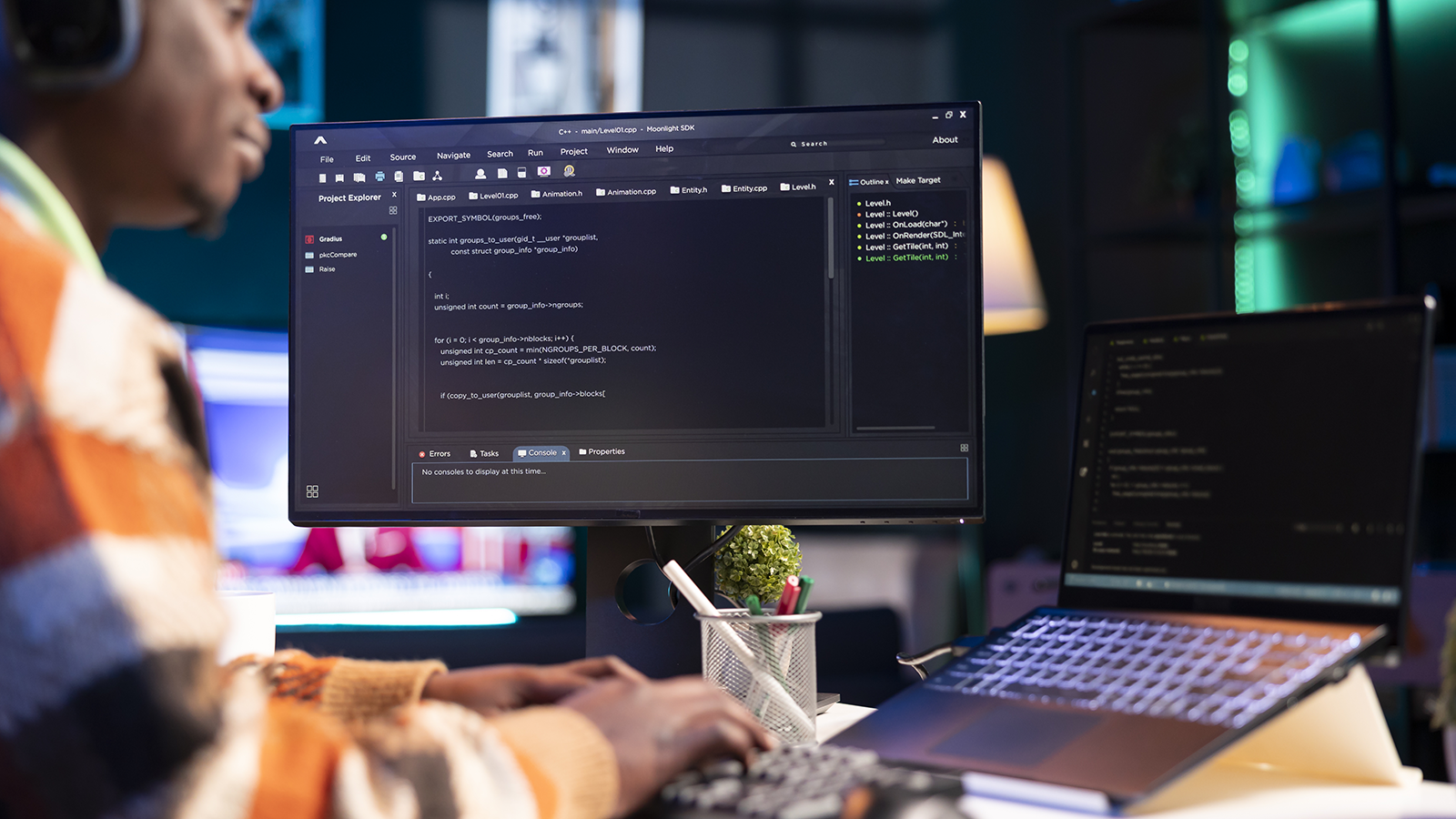 african american male software developer working on coding using laptop screen and external monitor